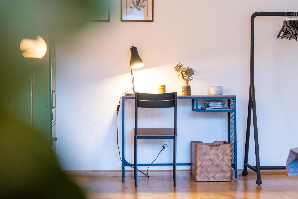 a desk with a chair and a table with a lamp at Gemütliche Wohnung Nähe Uni in Basel
