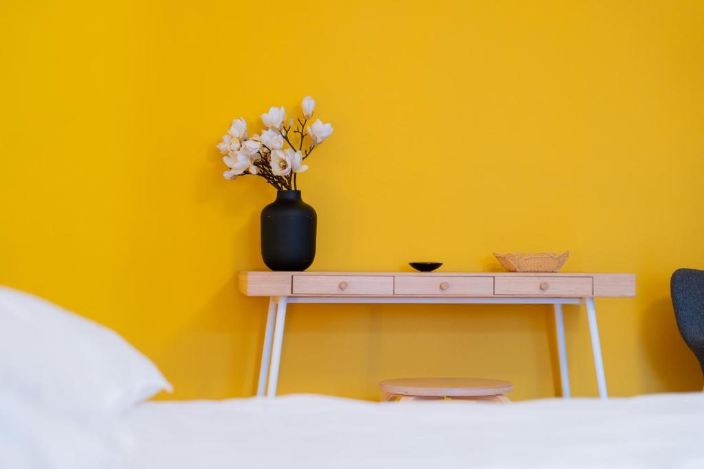 a table with a vase of flowers on a yellow wall at Gemütliche Wohnung Nähe Uni in Basel