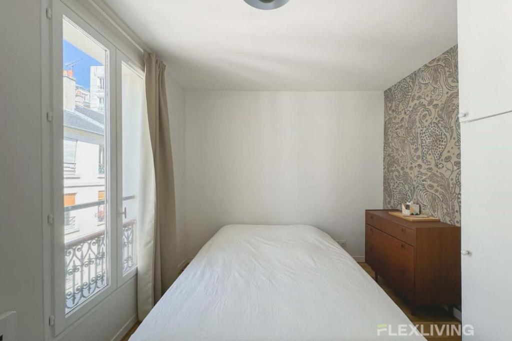une petite chambre avec un lit et une fenêtre dans l'établissement Flexliving - Studio - Durantin, à Paris