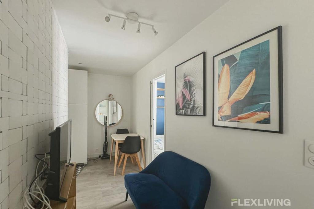 un salon avec une chaise bleue et des photos murales dans l'établissement Flexliving - whole flat - Bonnet, à Paris