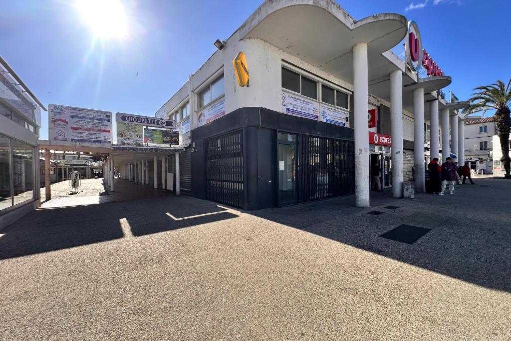 un bâtiment avec des gens qui marchent devant dans l'établissement L'Escapade Salée - A 100 mètres de la plage et en plein coeur de ville, au Grau-du-Roi