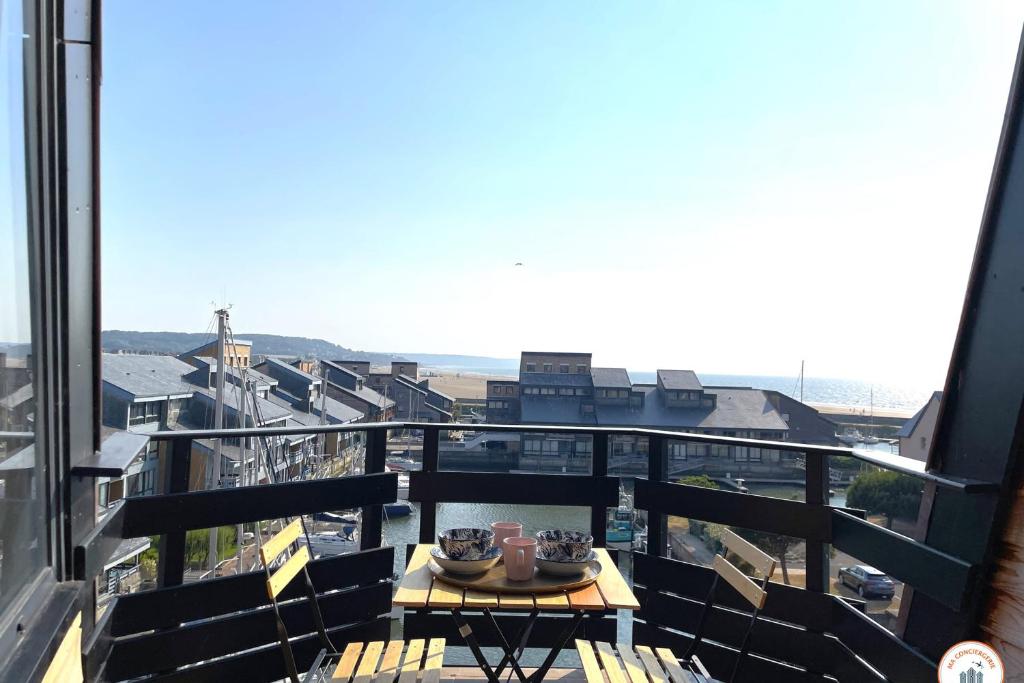 une table sur un balcon avec vue sur une ville dans l'établissement La Vie en Rose - Terrasse vue Mer - Plage - Marina, à Deauville