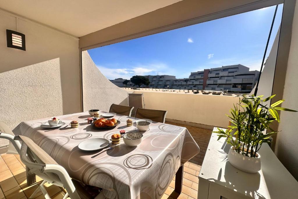 une table avec un chiffon de table blanc sur un balcon dans l'établissement Le Catamaran - Studio proche de la mer avec terrasse, au Grau-du-Roi