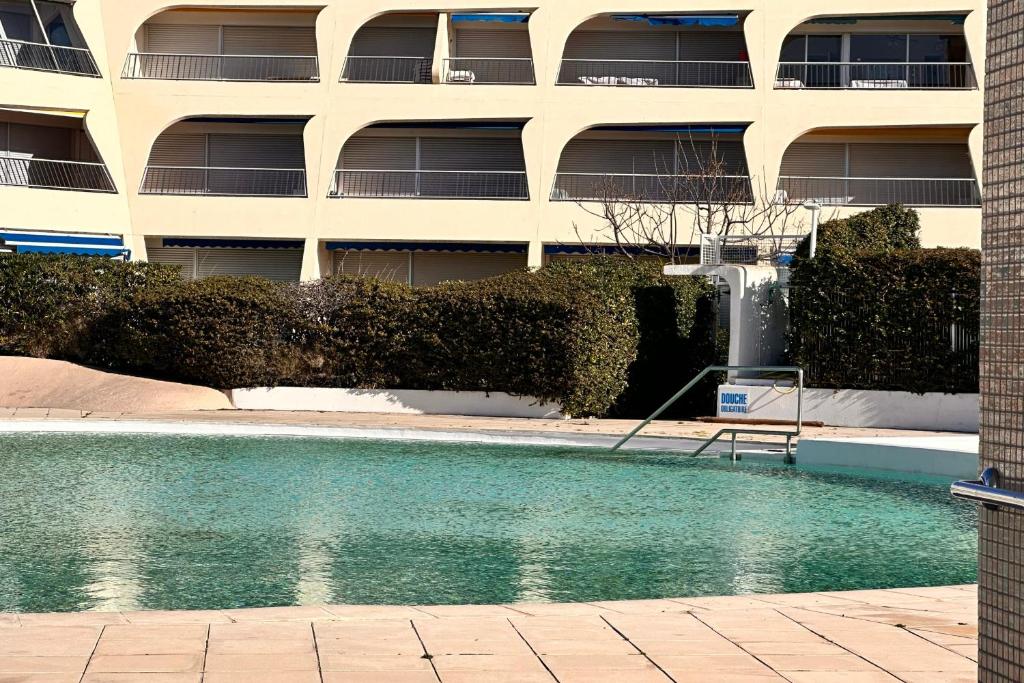 une piscine devant un immeuble dans l'établissement Studio Les Jardins du Port Port Camargue avec piscine à 2 pas de la plage, au Grau-du-Roi