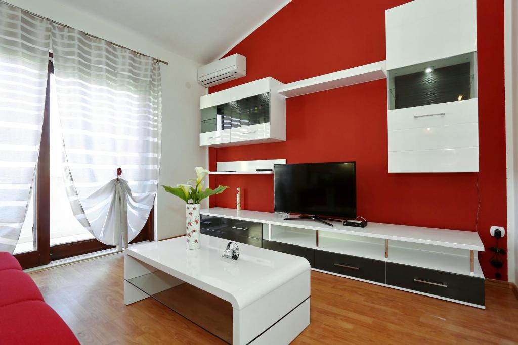 a living room with a red wall with a tv at Apartments Maslina Božava in Božava