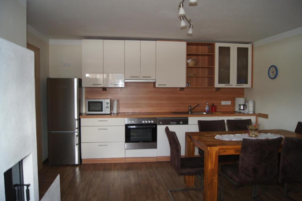 a kitchen with white cabinets and a wooden table with a dining room at Appartement Felix in Kaprun