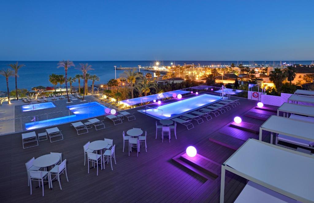 a view of a pool at night with tables and chairs at Hotel Ocean House Costa del Sol, Affiliated by Meliá in Torremolinos