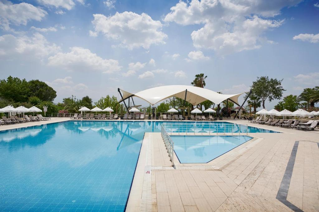 una piscina en un complejo con sillas y sombrillas en Richmond Pamukkale Thermal, en Pamukkale