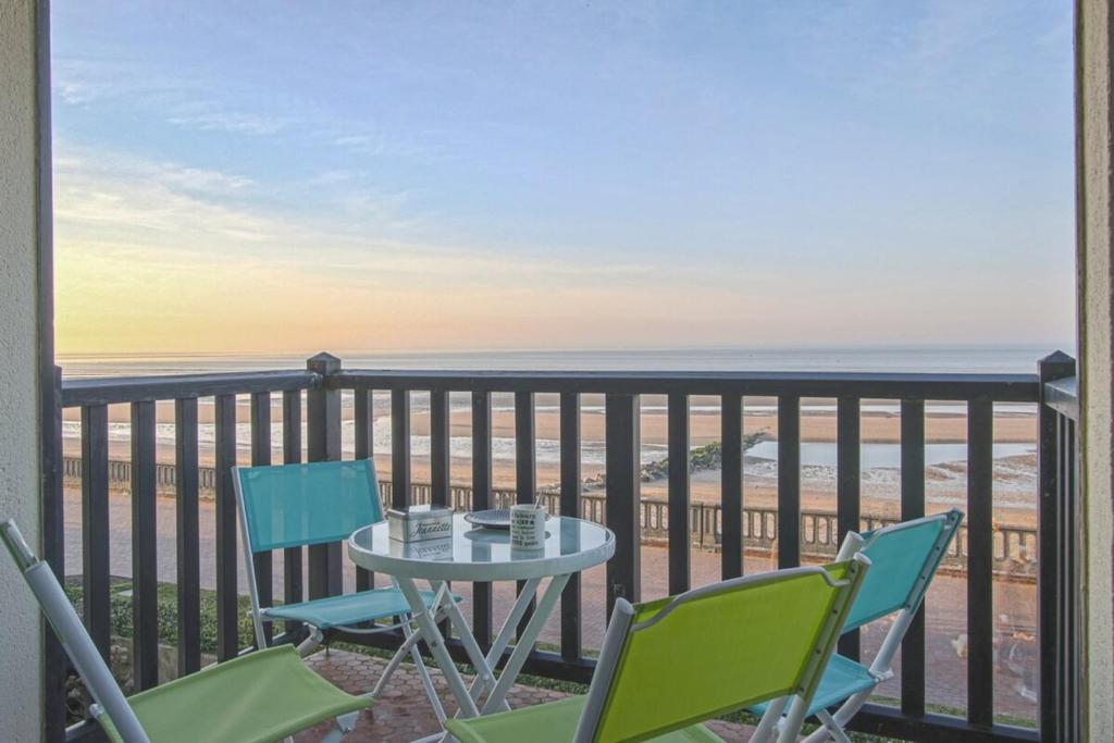 une table et des chaises sur un balcon avec vue sur l'océan dans l'établissement Appartement face à la mer, à Cabourg