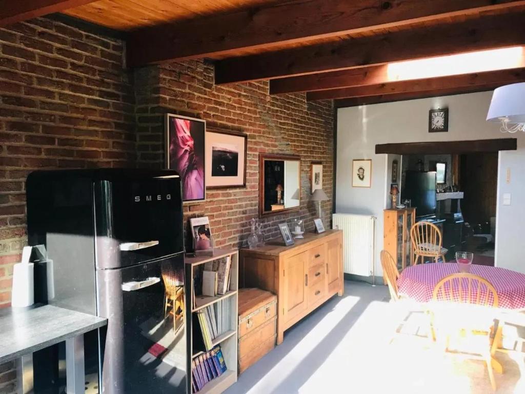 a kitchen with a black refrigerator and a brick wall at Family home in Thon, garden and terrace 100 m² in Namêche
