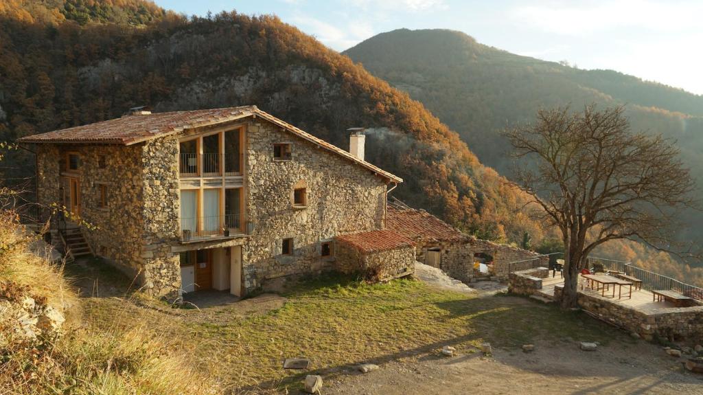 an old stone house on a hill with a mountain at Mas rural El Negre in Ogassa