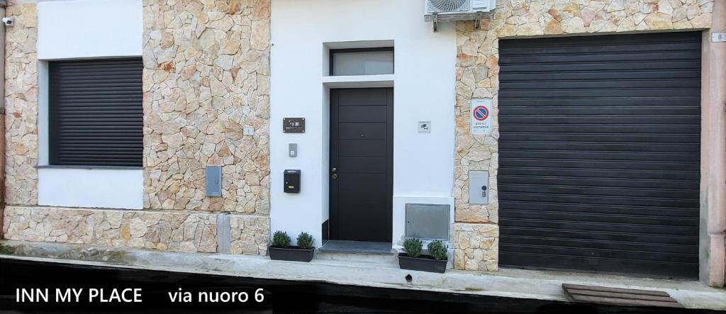 a building with two black garage doors on it at INN My Place in Selargius