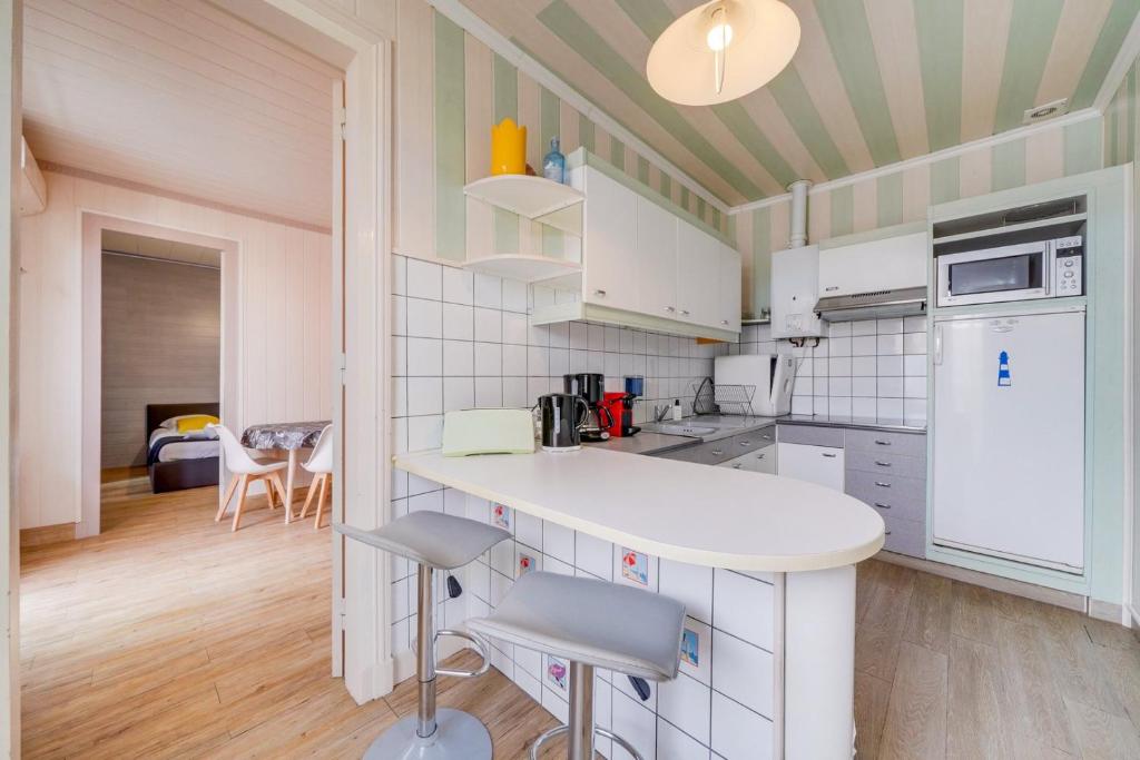 - une cuisine avec un comptoir et des chaises dans l'établissement Appartement St Arnaud, à Arcachon