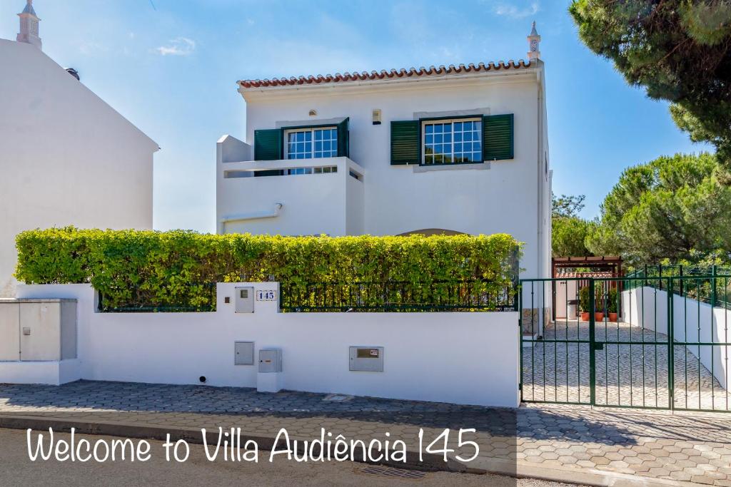 a white house with green windows and a fence at Villa Audiência 145 in Castro Marim
