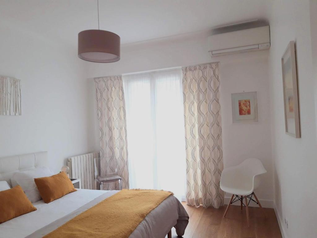 une chambre avec un lit et une fenêtre avec une chaise dans l'établissement Luxueux 3P en plein cœur de Nice, à Nice