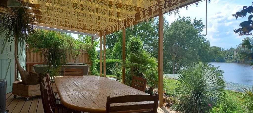 - une table en bois sur une terrasse avec vue sur le lac dans l'établissement Gîte au bord du Tarn avec ponton et spa, à Marssac-sur-Tarn