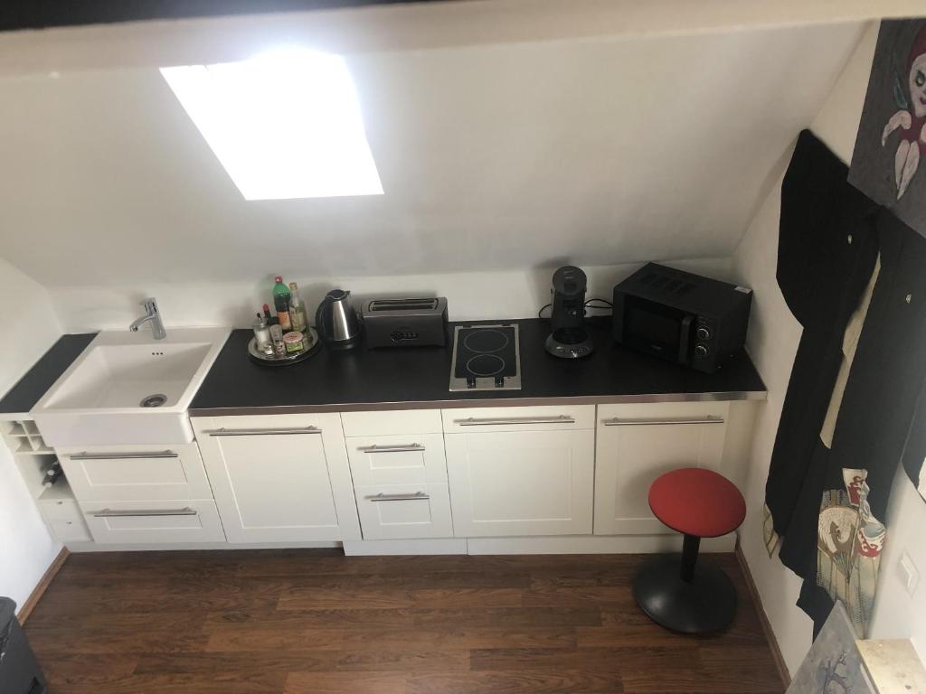 a small kitchen with white cabinets and a sink and a red stool at Bel Art Atelier mit großem Parkplatz in Haan