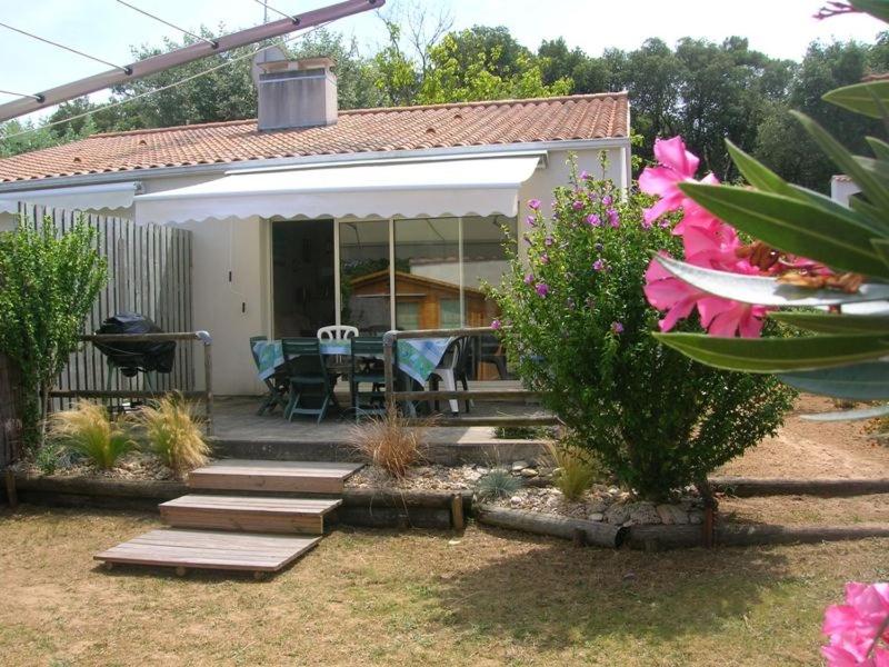 une maison avec un patio avec une table et des chaises dans l'établissement Vacances en bordure de forêt domaniale, à La Tranche-sur-Mer