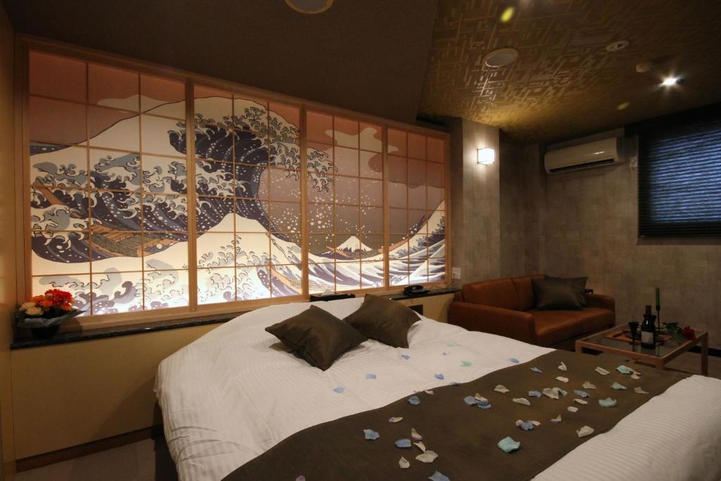 a bedroom with a bed and a window with a painting at Hotel京都 in Zentsuji