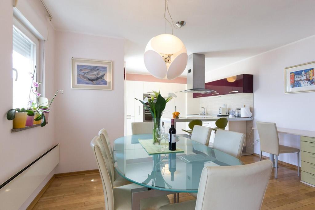 a dining room with a glass table and white chairs at Apartman Sara s predivnim pogledom na more in Matulji