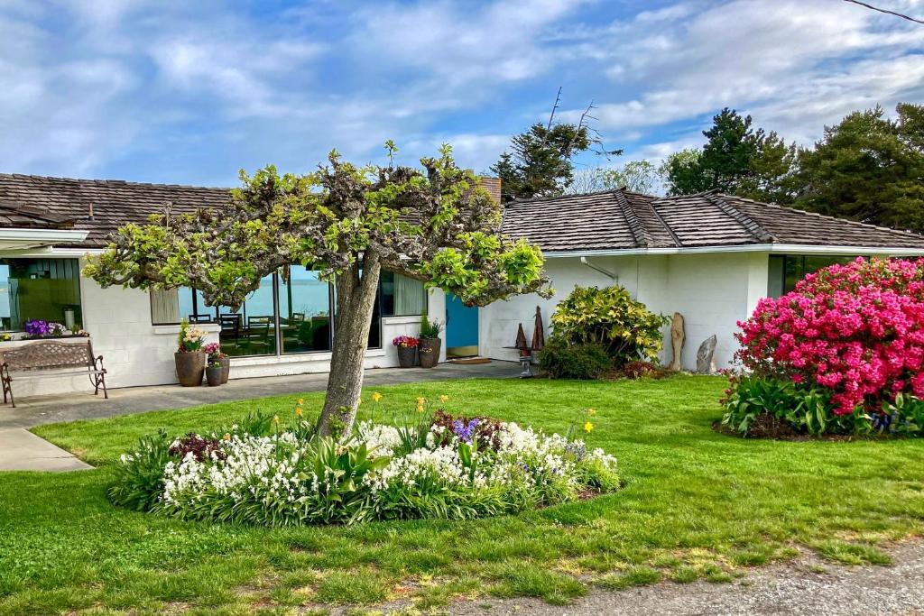 a house with a tree and flowers in the yard at Windrift House in Sequim