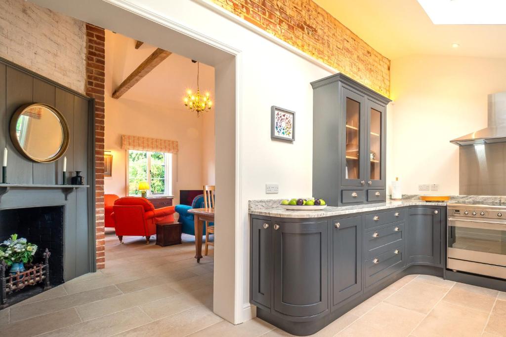 a kitchen with gray cabinets and a living room at Luxurious rural retreat - Holt Coach House in Sudbury