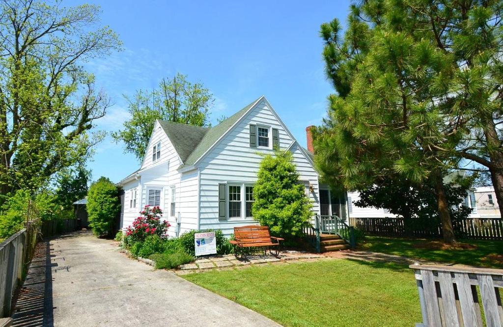 una casa bianca con una panchina in cortile di Sea Charm - Downtown, Screened porch! a Chincoteague