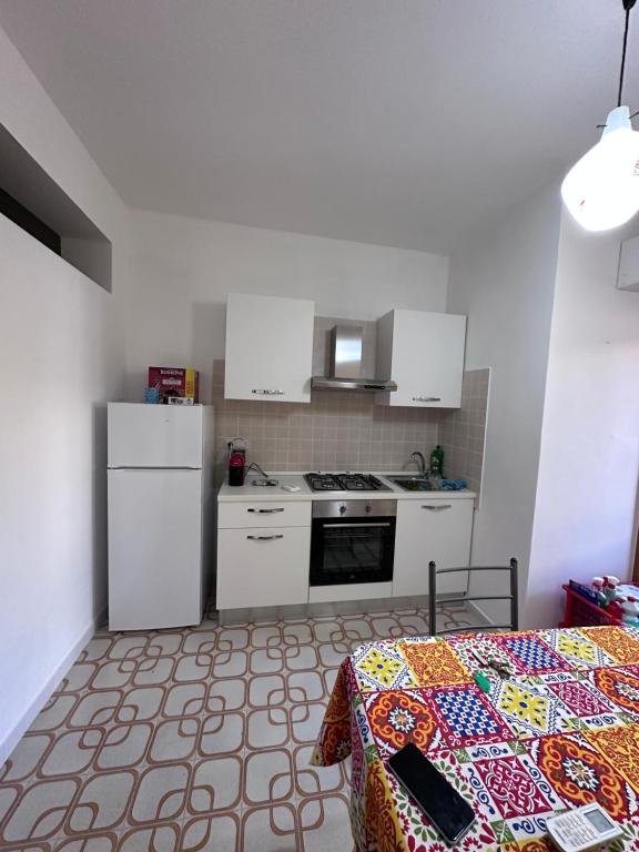 a kitchen with white cabinets and a table with a bed at Casa Modesto Monasterace Marina in Marina di Monasterace