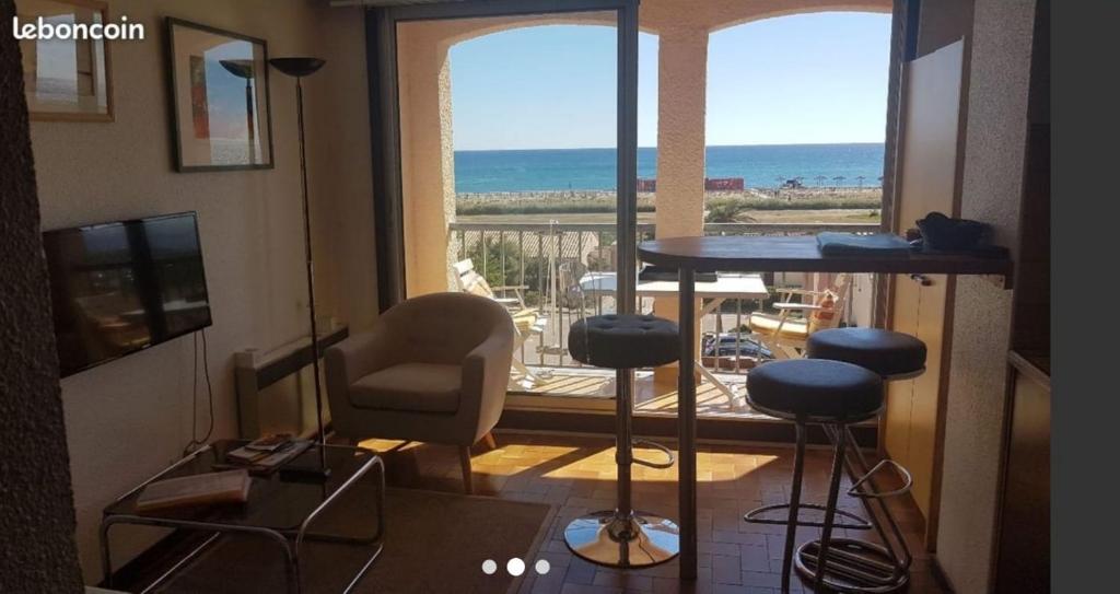Cette chambre dispose d'une table, de chaises et d'un balcon. dans l'établissement Coeur du village Barcarès accès plage direct studio vue mer exceptionnelle, au Barcarès