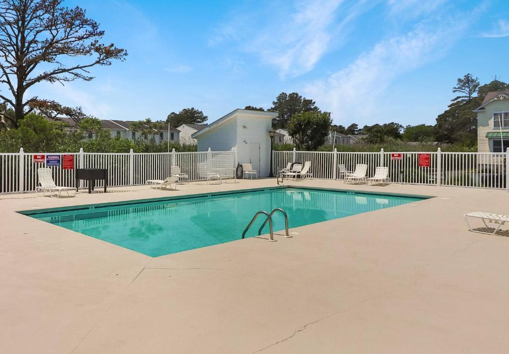a swimming pool with chairs and a fence at Seas the Day - Water views, Shared pool! in Chincoteague