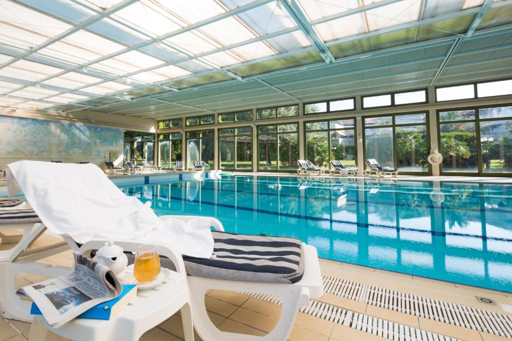 a hotel room with a pool and chairs at Hotel Villa Undulna - Terme della Versilia in Cinquale