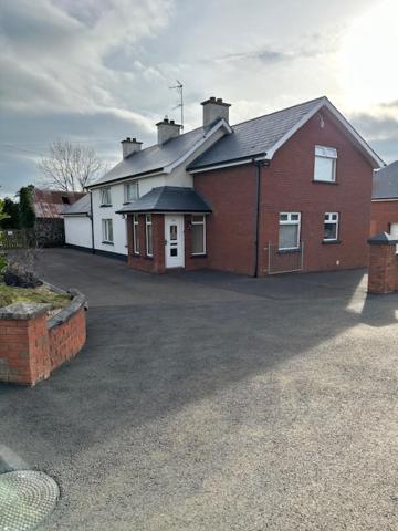 a large red and white house with a driveway at Farmhouse at 93 in Portglenone