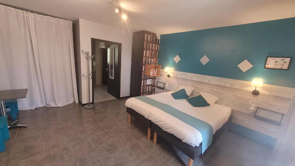 a bedroom with a large bed with a blue wall at Hotel La Peyrade in Cajarc