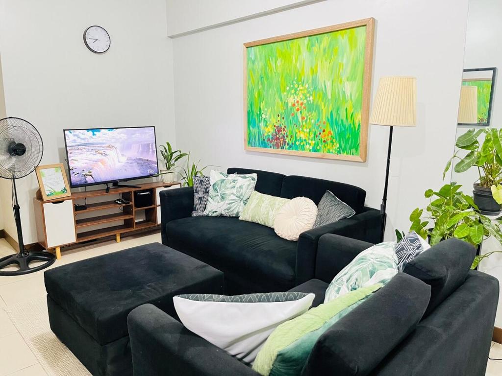 ein Wohnzimmer mit zwei Sofas und einem Fernseher in der Unterkunft Acacia Estates' The Getaway Taguig, Evergreen in Manila