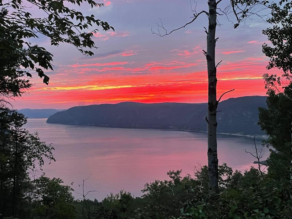 a sunset over a lake with mountains in the background at YOURTE du FJORD in Sacré-Coeur-Saguenay