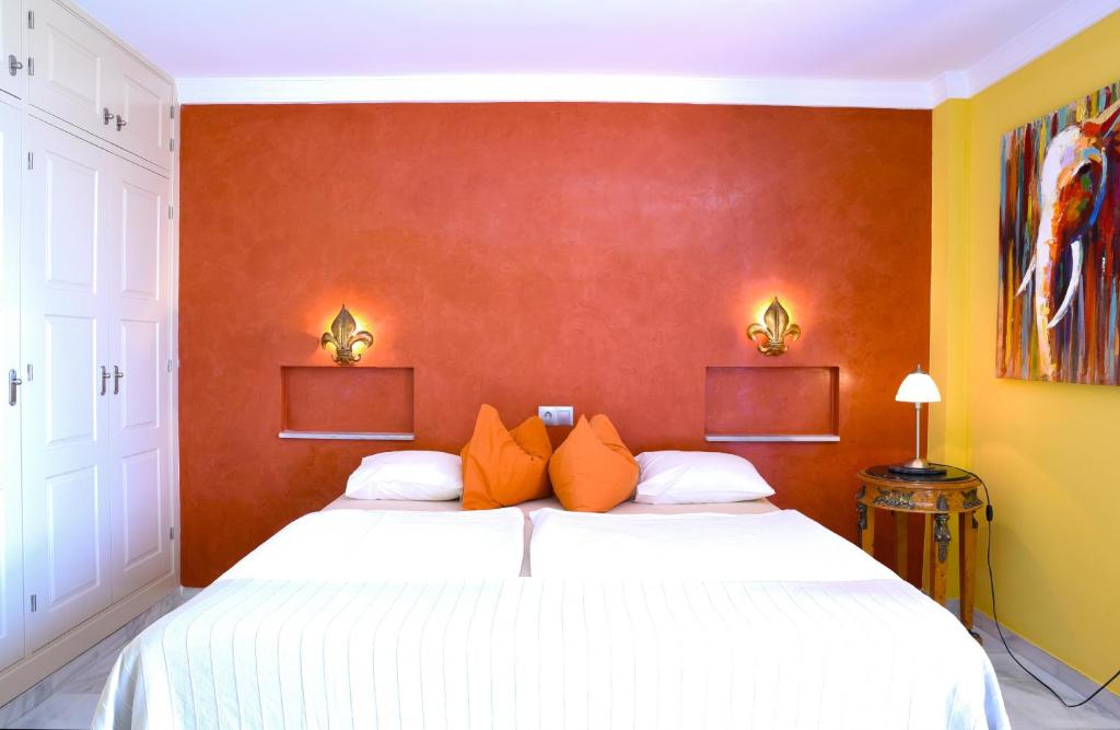 a bedroom with two beds with white sheets and orange pillows at Estudio superior con vistas y pequeña terraza en Maro in Maro