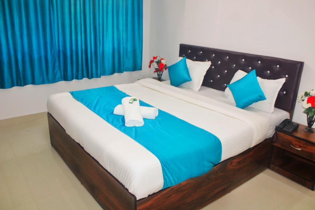 a bedroom with a large bed with blue curtains at Sadanand Home in Navi Mumbai