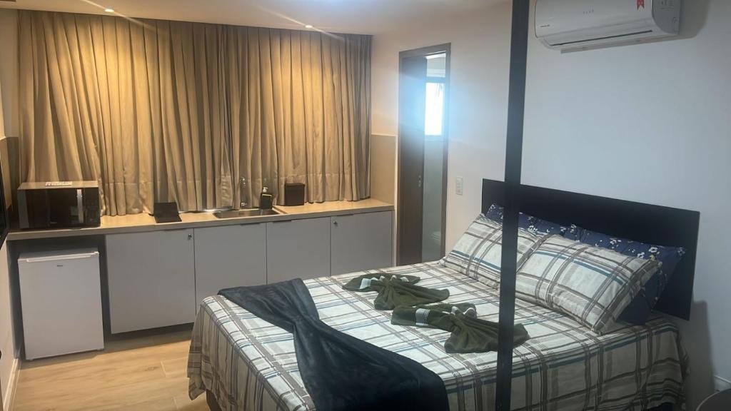 a bedroom with a bed and a kitchen at Flat Maravilhoso na Praia de Cabo Branco in João Pessoa