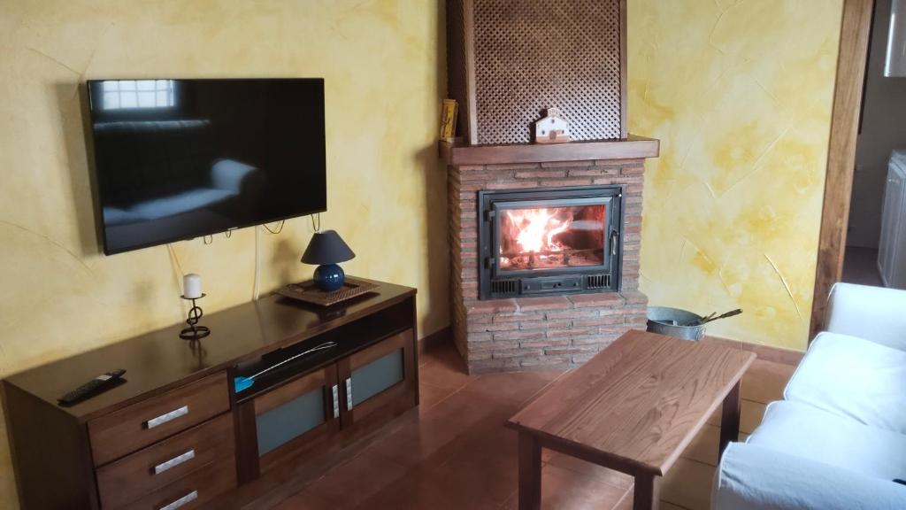 ein Wohnzimmer mit einem Kamin und einem Flachbild-TV in der Unterkunft Casa Rural Cuatro Vientos in Santiago-Pontones