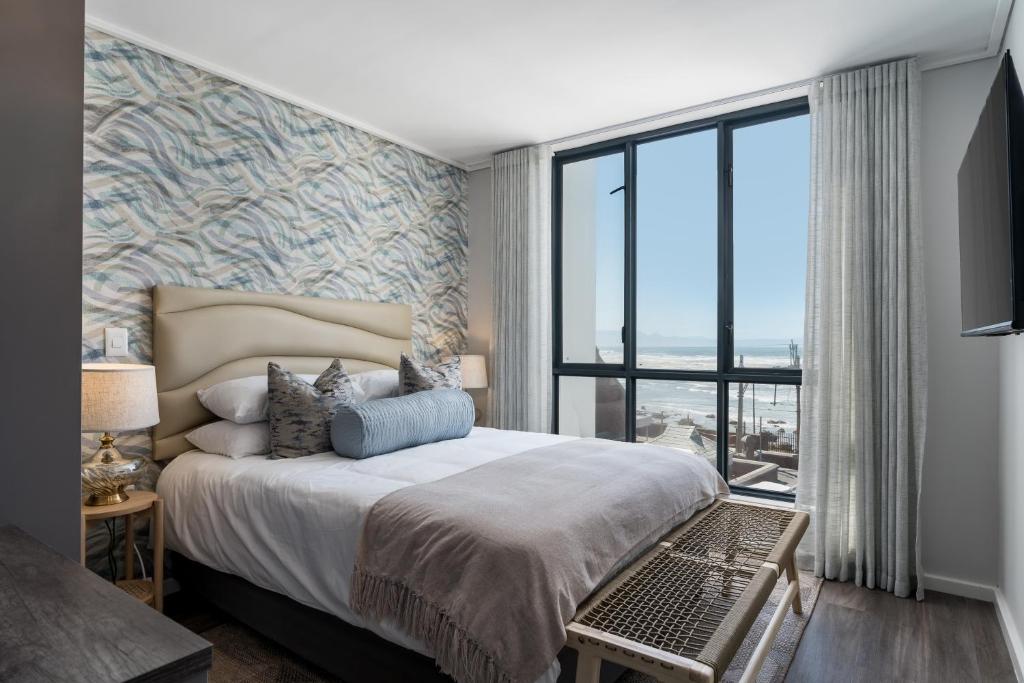 a bedroom with a large bed and a large window at Luxury by the Sea Muizenberg Beachfront in Muizenberg