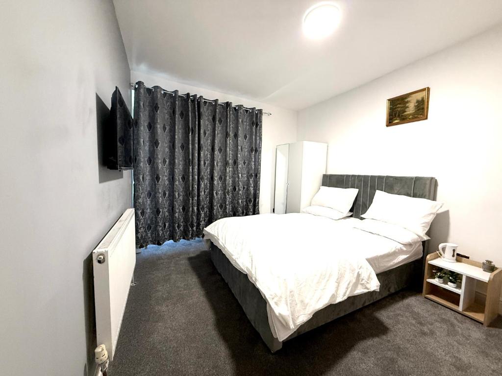 バーミンガムにあるEn-suite Rooms in beautiful Bournville Villageのベッドルーム(白いベッド1台、黒いカーテン付)