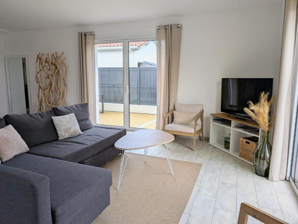 un salon avec un canapé et une télévision dans l'établissement Maison neuve de plain-pied avec extérieur, à Pornic