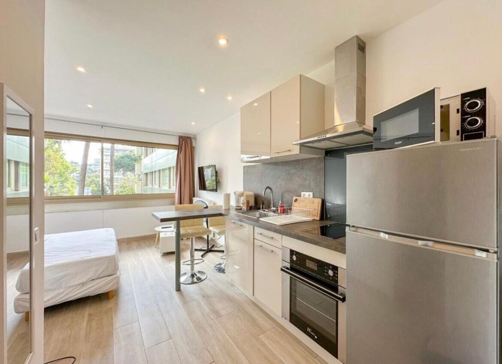 een keuken met een roestvrijstalen koelkast en een tafel bij Studio Moderne Cannes - Parking - Proche de la plage in Cannes