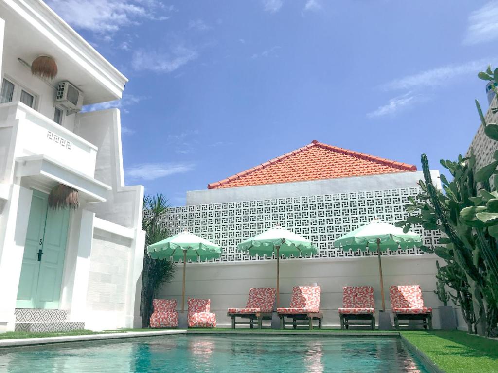 a pool with chairs and umbrellas next to a building at Kaktus Boutique Apartments Bali - ADULTS ONLY in Legian