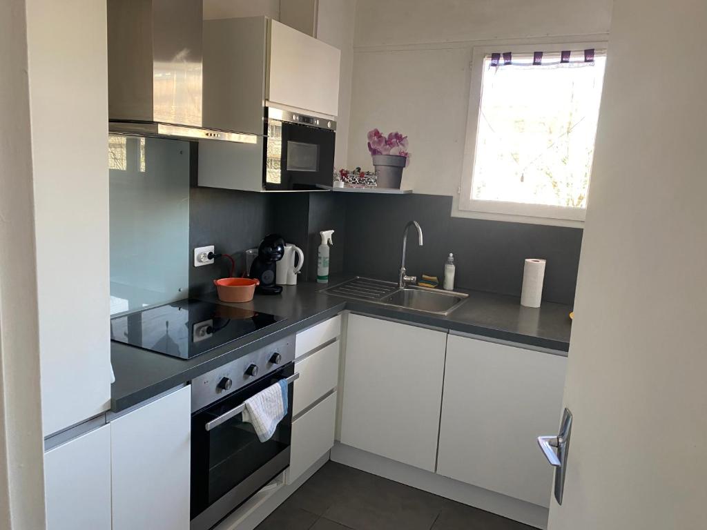 une cuisine avec des armoires blanches et un évier dans l'établissement F2 avec grand balcon quartier gare!, à Metz