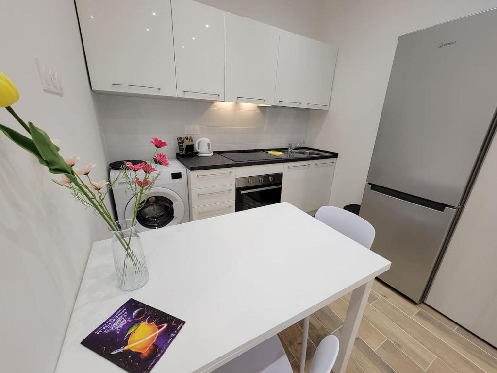 a white kitchen with a table and a refrigerator at Orangerie- Menton centro-ideale inverno in Menton