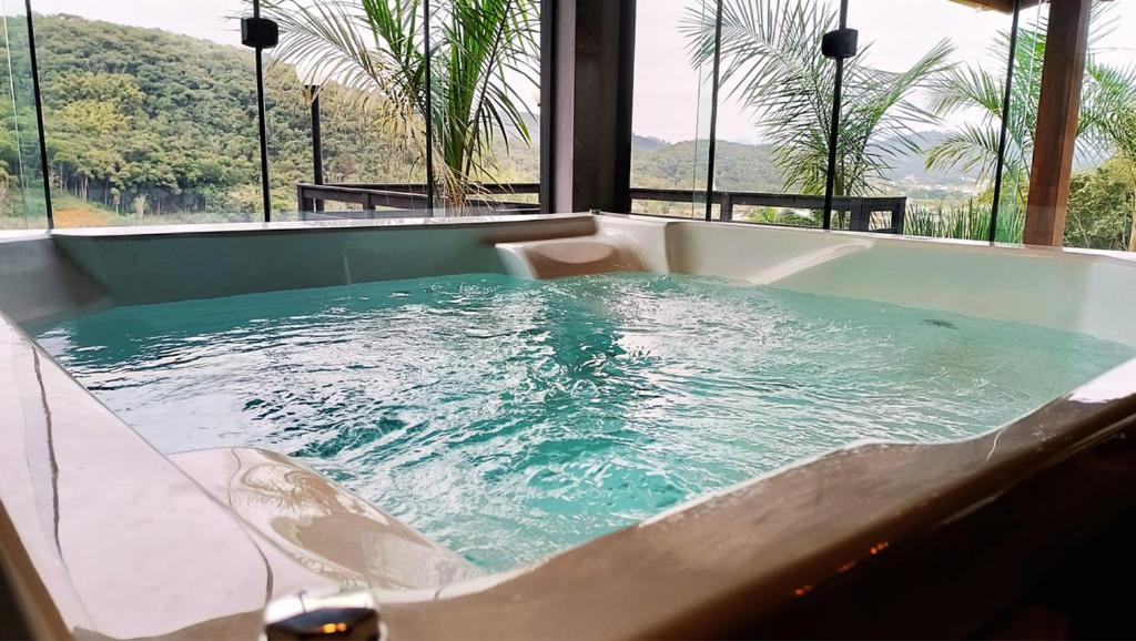 a jacuzzi tub with blue water in a room at Cabana Montana Viva Cada Momento in Guaramirim