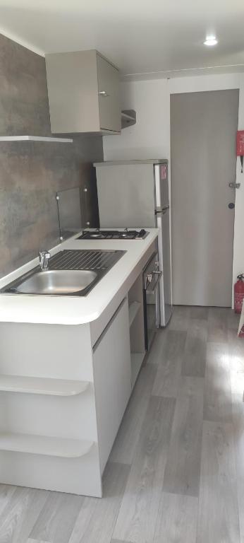 une cuisine blanche avec un évier et une cuisinière dans l'établissement Mobile home A32, à Sérignan