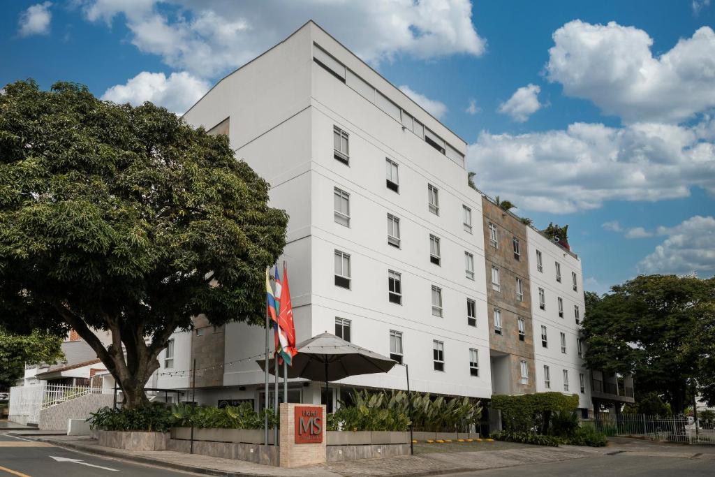 un edificio bianco con un ombrello davanti di Hotel MS Ciudad Jardin a Cali