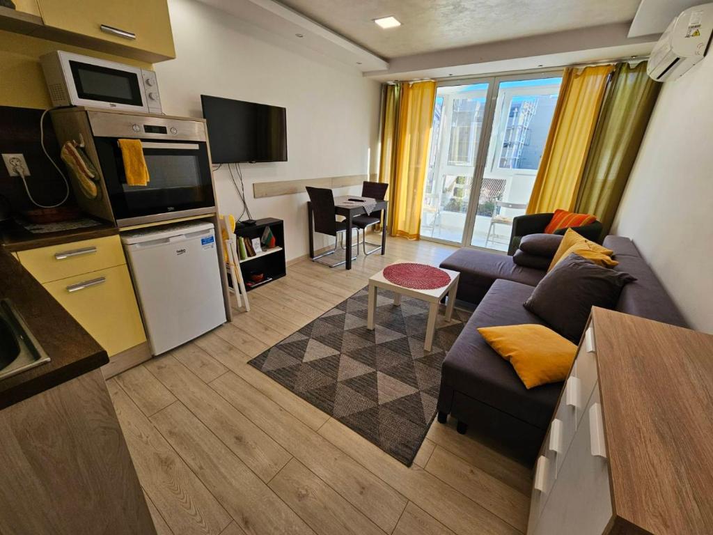Una pequeña sala de estar con un sofá y una cocina. en Данделион, en Burgas